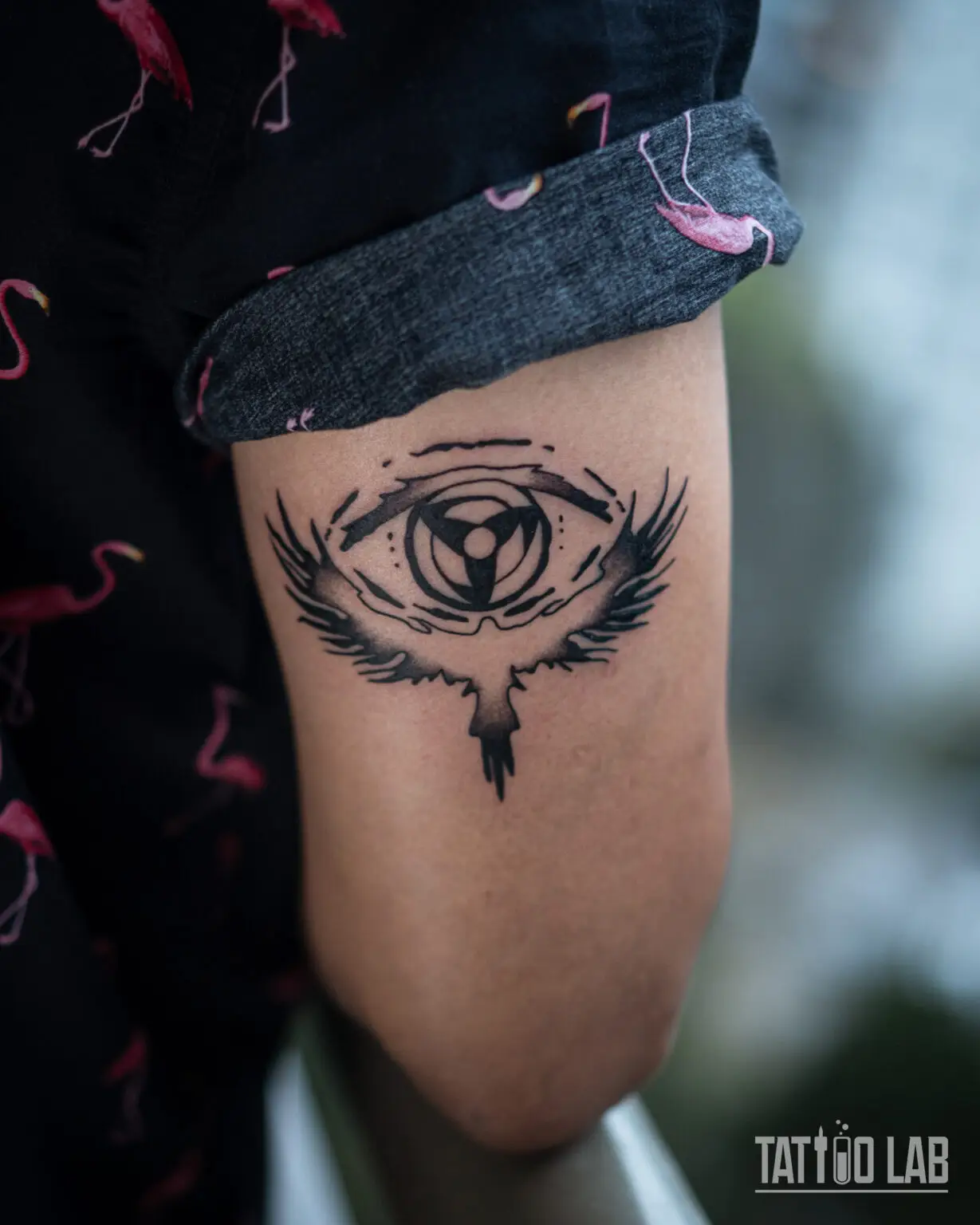 Bold blackwork winged eye tattoo with a three-part symbol in the pupil on the back of the upper arm, Tattoo Lab, Halifax