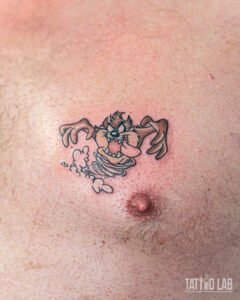 Colour cartoon Tasmanian Devil tattoo on the chest, spinning in a dust cloud with bold outlines