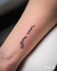 Fine line script tattoo reading "you can." on the forearm, a small minimalist motivational quote
