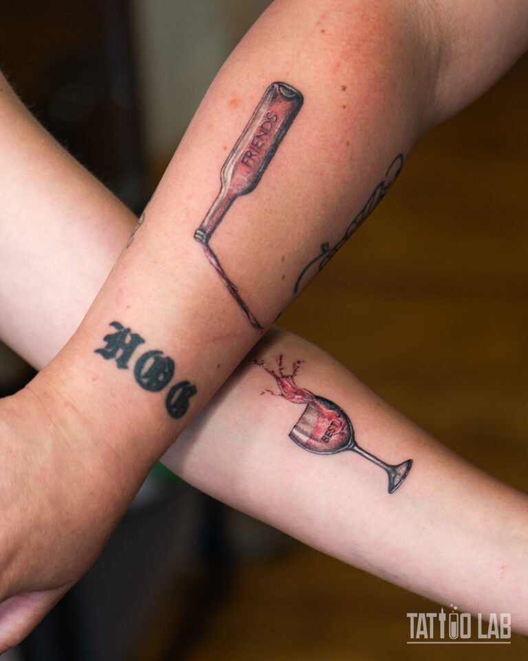 Matching best friends tattoos, a "FRIENDS" wine bottle pouring into a "BEST" wine glass, in colour realism