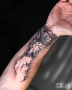 Black and grey realism wolf tattoo on the forearm, its breath curling into a smoky spirit shape