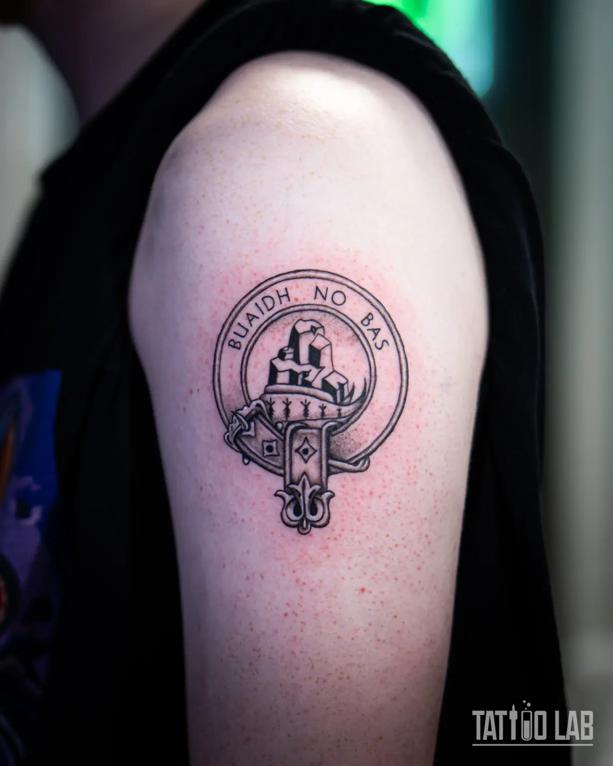 Black and grey Scottish clan crest badge tattoo on the upper arm with the motto Buaidh No Bas, Tattoo Lab, Halifax