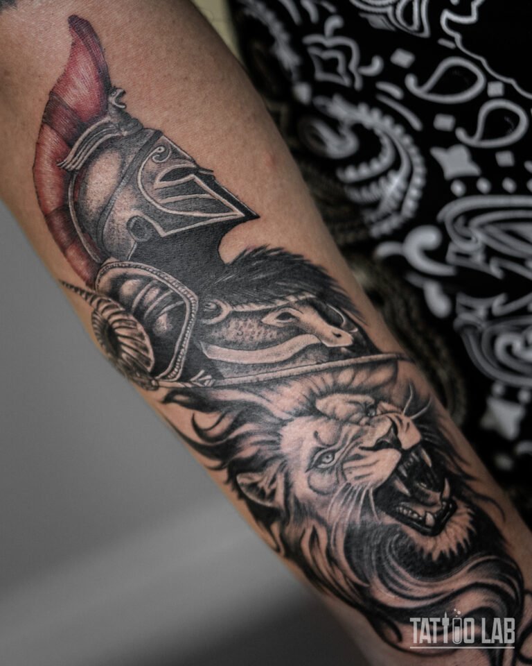Realism Spartan helmet and roaring lion tattoo on the arm, black and grey with a red plume