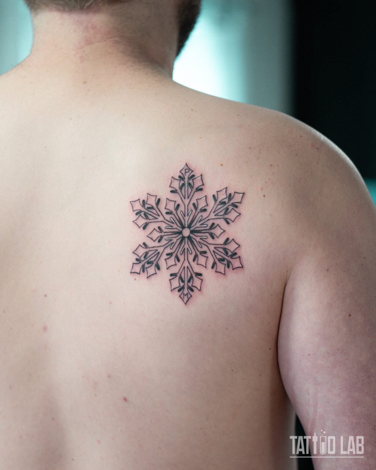 Ornamental black linework snowflake tattoo with leaf-shaped details on the shoulder blade, Tattoo Lab, Halifax