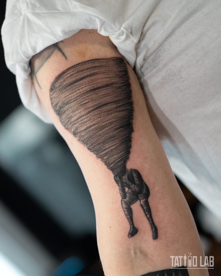 Creative tornado tattoo with seated figure integrated into the design, surreal black and grey work by Tattoo Lab Halifax Nova Scotia.
