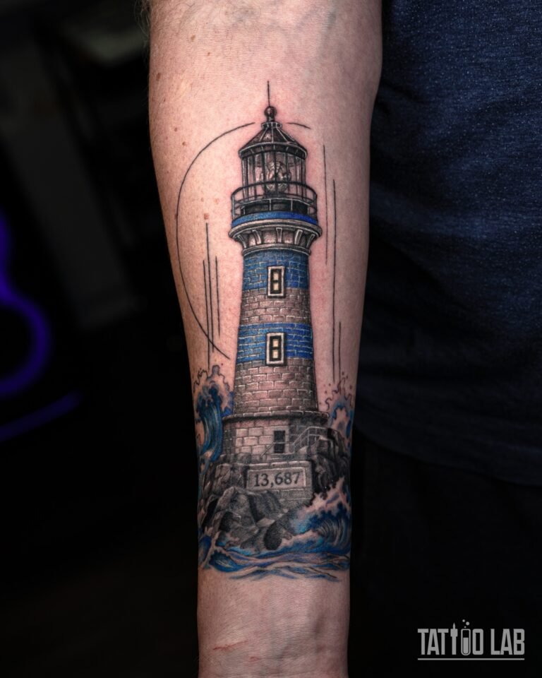 Black and grey realism lighthouse tattoo with crashing blue waves on a forearm