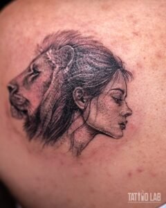 Black and grey realism tattoo of a lion head merging into a woman’s profile with flowing hair on the shoulder blade