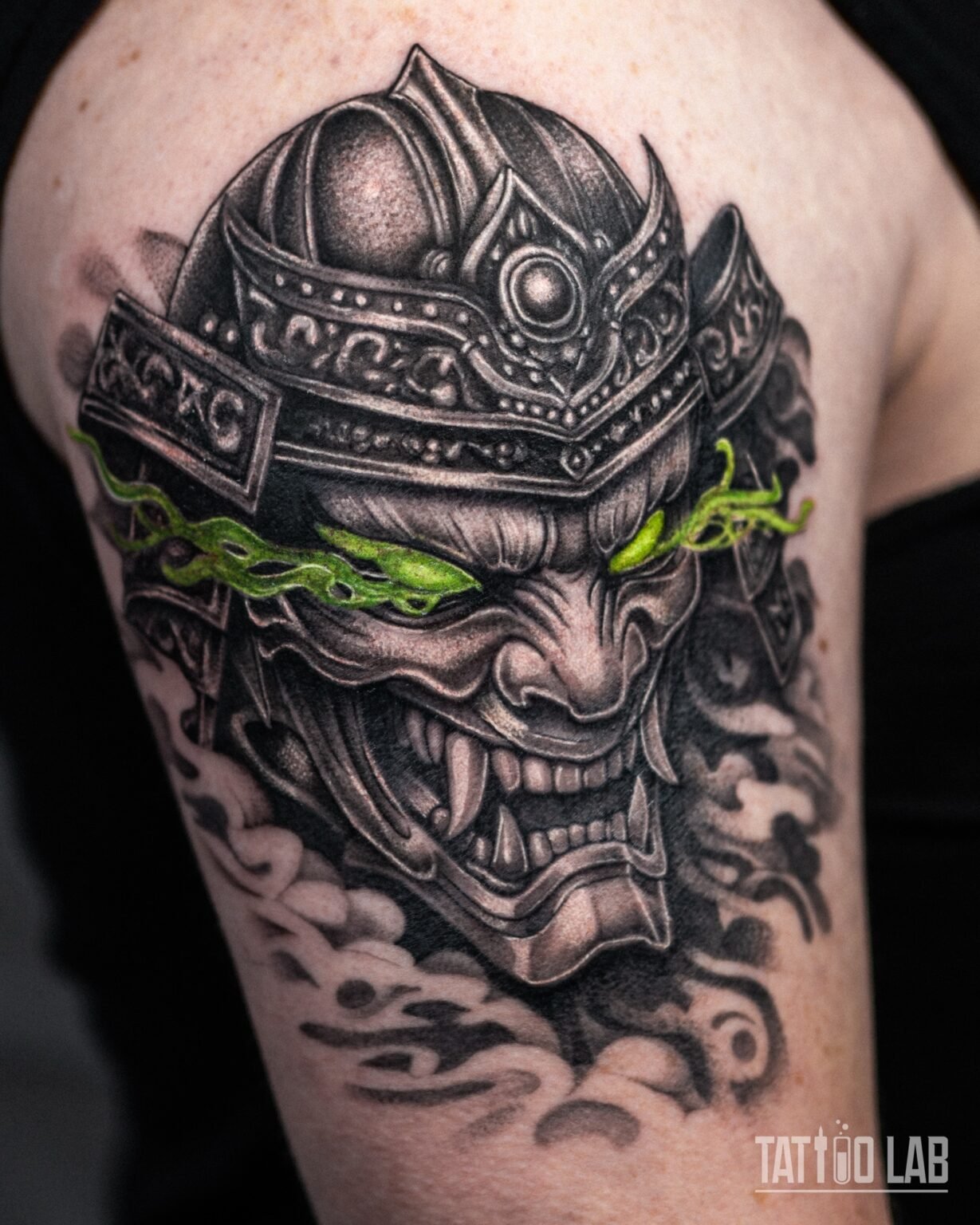Close-up of the oni mask with glowing green eyes under the samurai helmet, black and grey with smoke, Tattoo Lab, Halifax