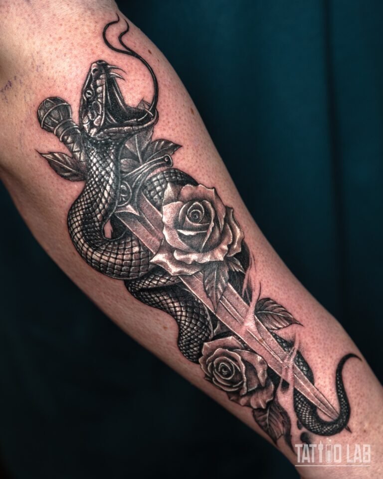Black and grey realism tattoo of a snake coiled around a dagger with two roses and leaves on the forearm