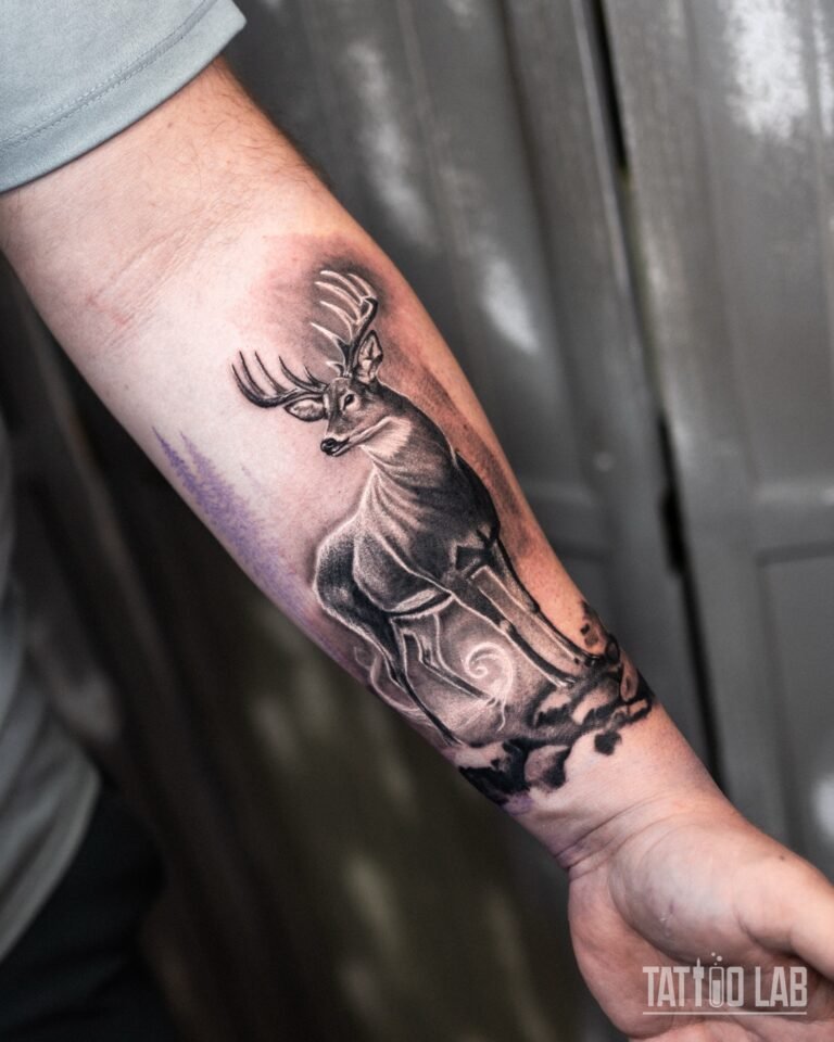 Black and grey stag tattoo on rocks on the inner forearm, before the pine forest background was added