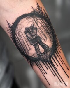 Black and grey tattoo of a couple embracing in a winter forest inside a brushstroke circle with ink drips on the forearm