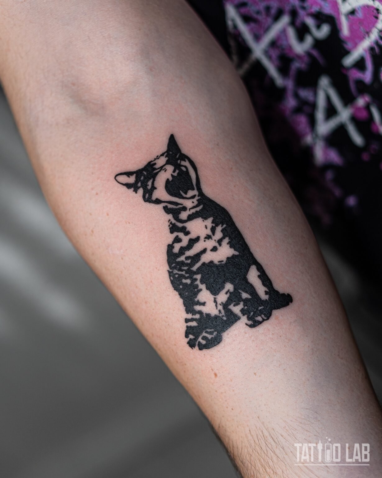 High-contrast solid black stencil-style tattoo of a sitting cat on the inner forearm, Tattoo Lab, Halifax