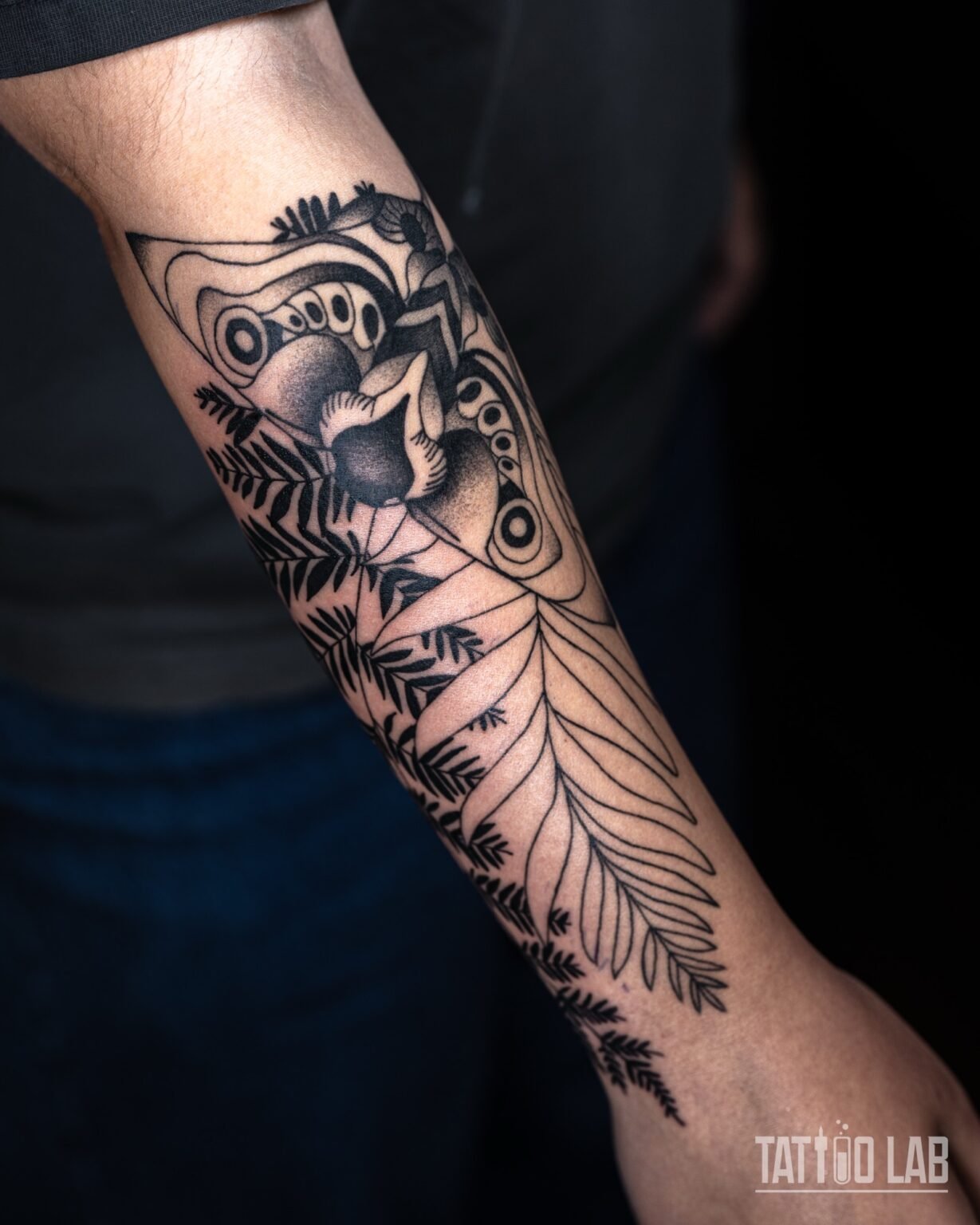 Blackwork tattoo of an ornamental moth with fern leaves on the forearm, inspired by the video game The Last of Us, Tattoo Lab, Halifax