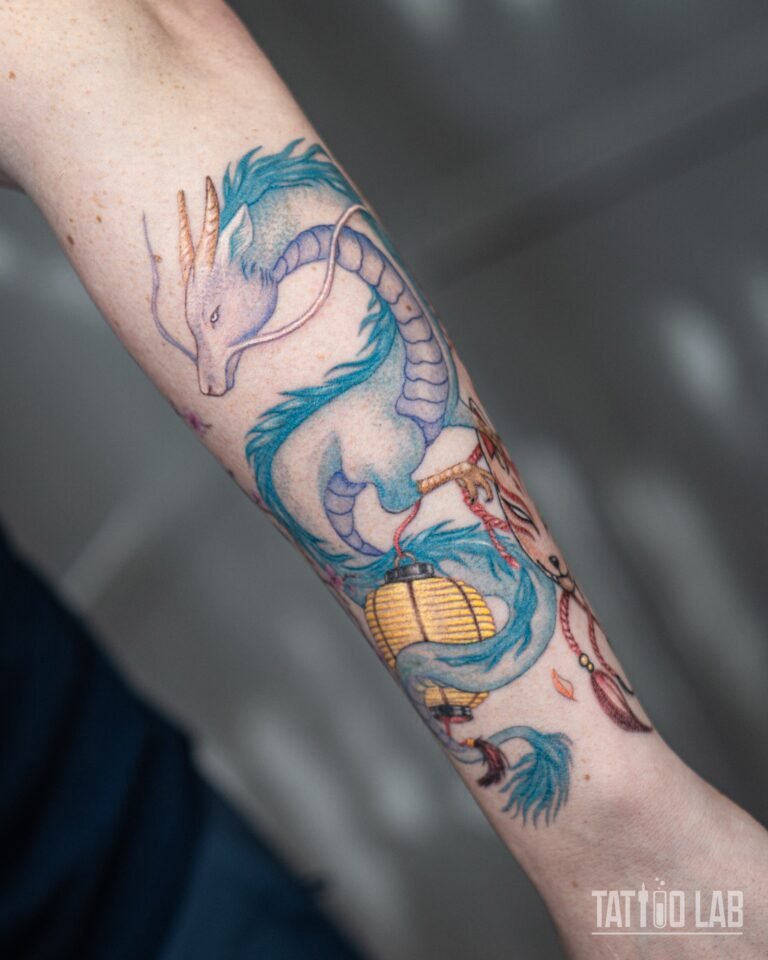 Pastel blue colour dragon tattoo holding a yellow paper lantern, anime-inspired forearm sleeve