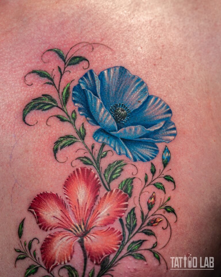 Colour realism tattoo of a blue poppy and a red hibiscus with fine green vines and leaves on the chest