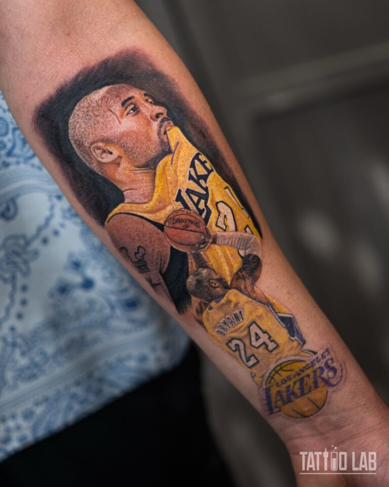 Colour realism Kobe Bryant tattoo on the forearm: a portrait in a Lakers jersey above a jump shot and the Lakers logo