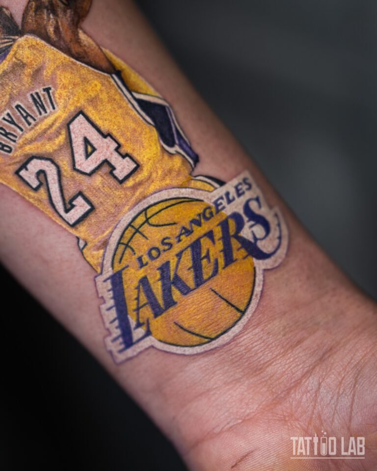 Close-up of a colour realism Lakers logo and gold jersey tattoo near the wrist, showing smooth colour blending
