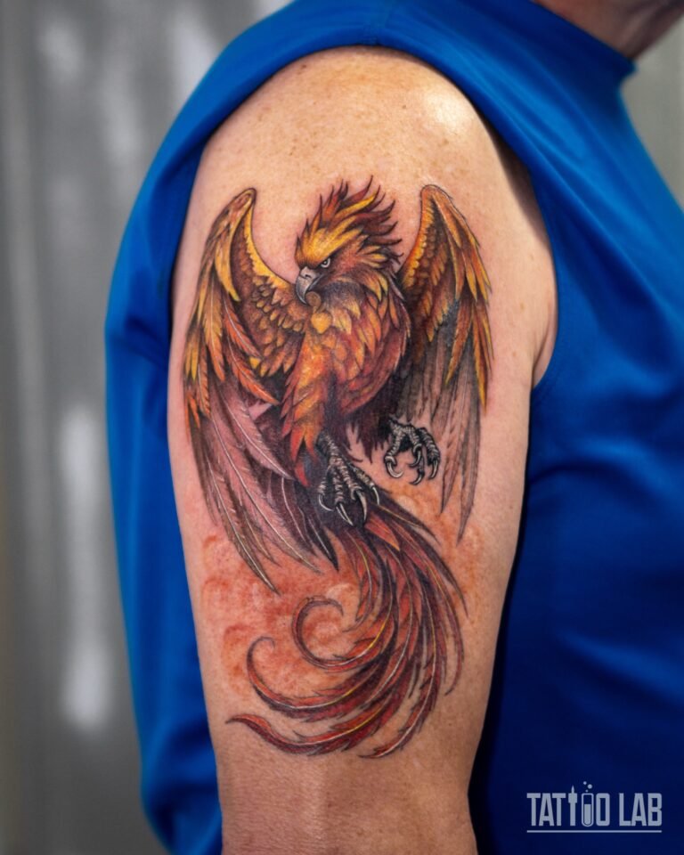 Colour realism phoenix tattoo with spread wings and curling red tail feathers on the upper arm