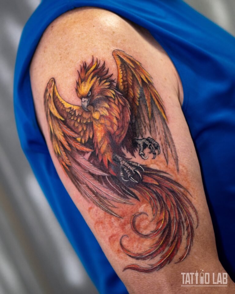 Closer view of a colour realism phoenix tattoo with layered yellow, orange and red feathers on the upper arm