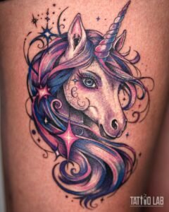 Colourful unicorn head tattoo with a flowing pink, purple and blue mane, sparkles and swirls on the thigh