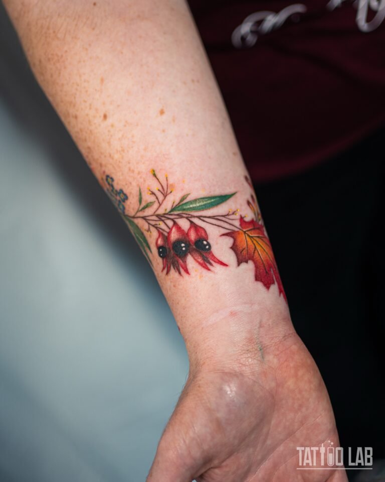 Colour tattoo band around the wrist with red desert pea flowers, a red maple leaf and fine green leaves
