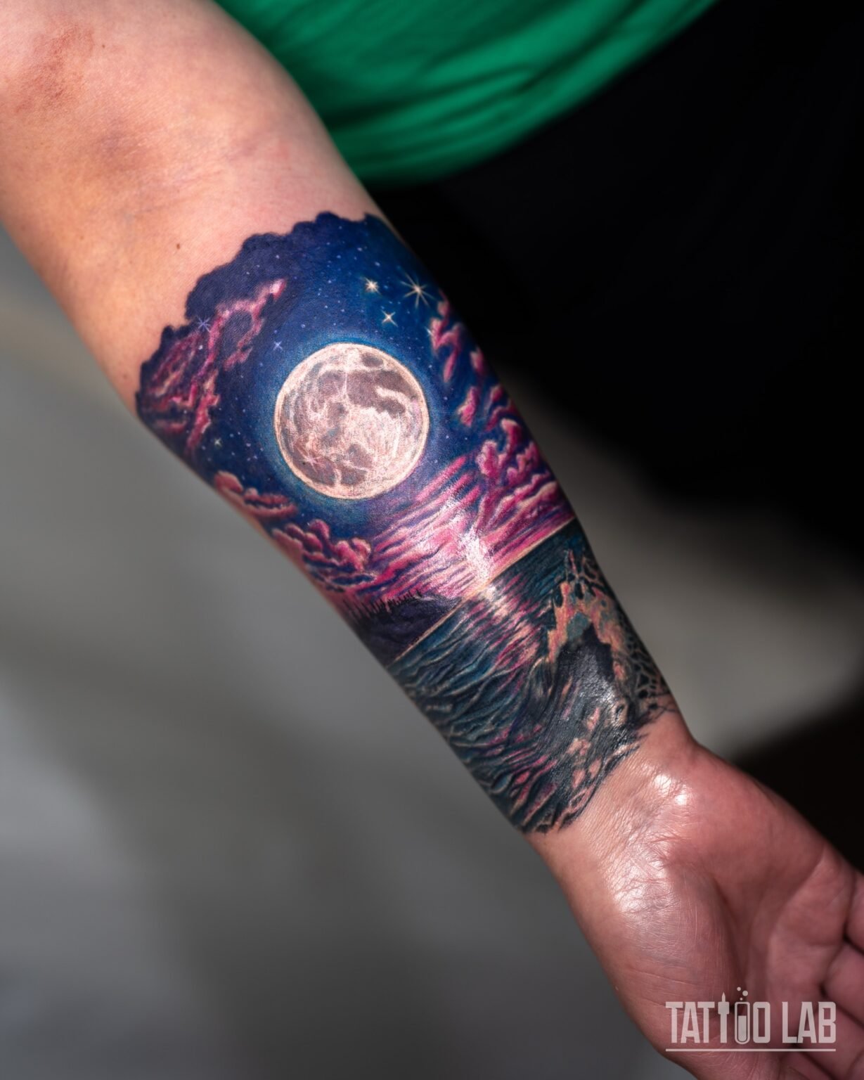Colour realism cover-up tattoo of a full moon over the sea with pink clouds and waves, wrapping the forearm, Tattoo Lab, Halifax
