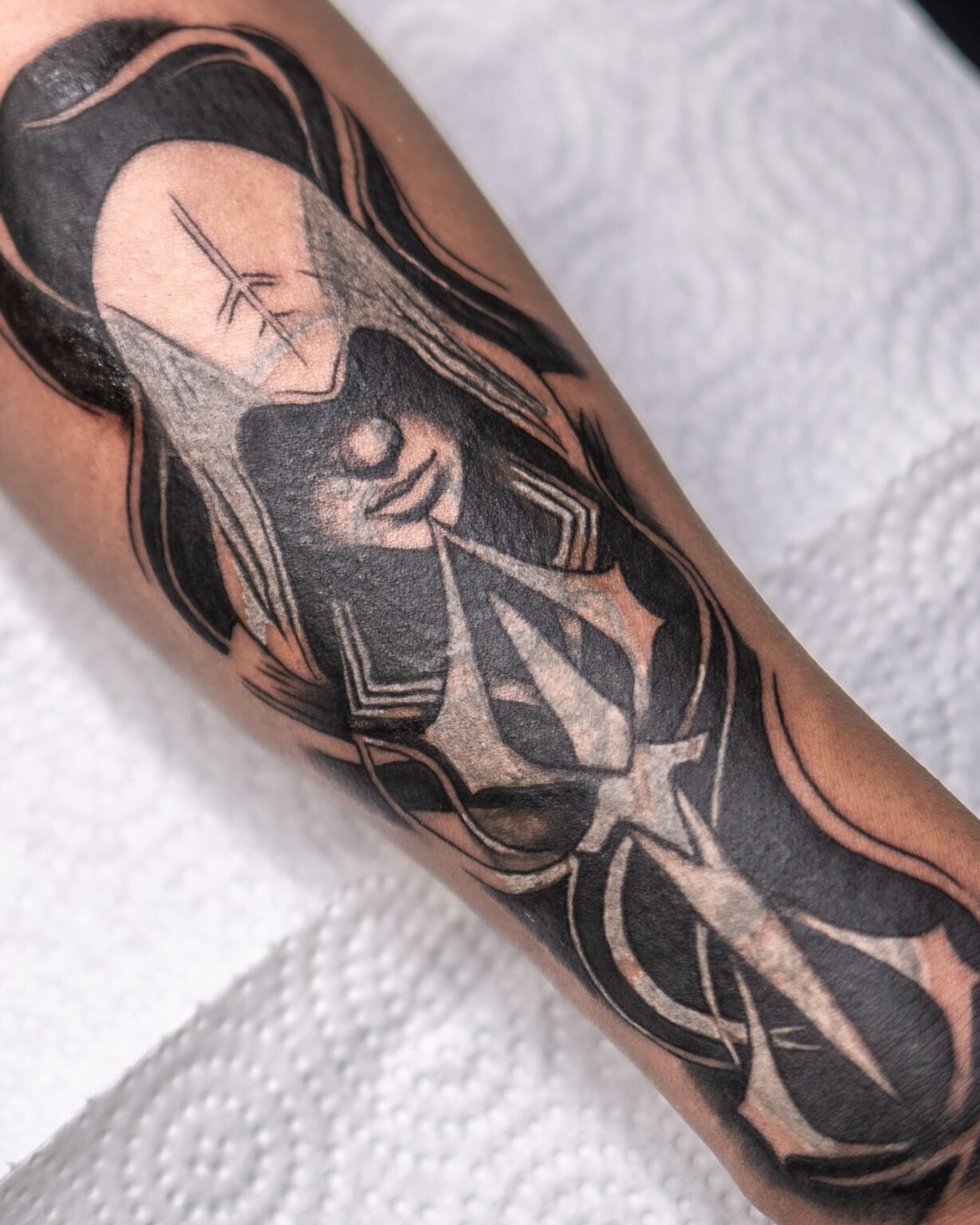 Blackwork cover-up tattoo of a long-haired figure with a trident in solid black, on the forearm, Tattoo Lab, Halifax