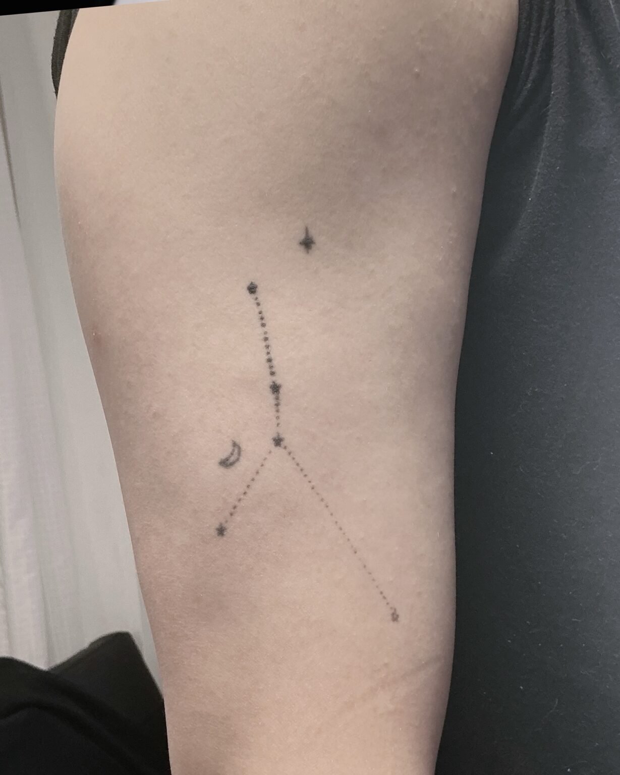 Fine line constellation tattoo with a crescent moon and small stars on the upper arm, before its cover-up at Tattoo Lab, Halifax