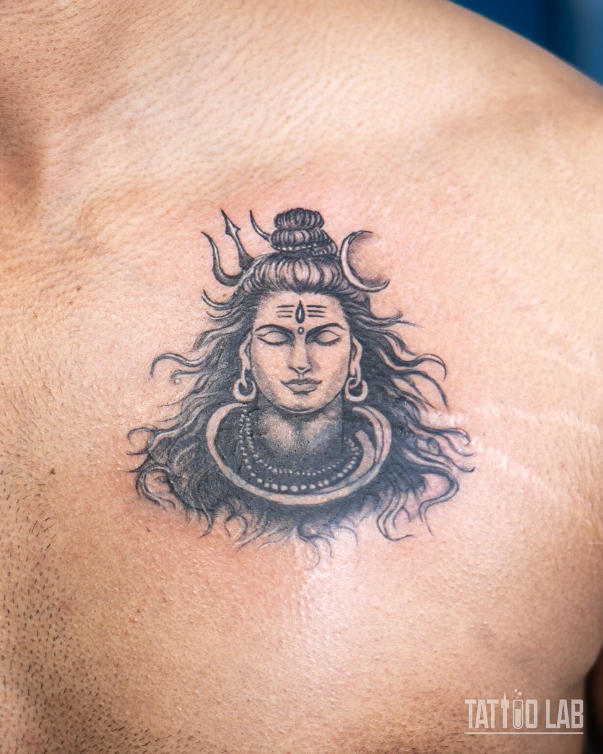 Black and grey realism cover-up tattoo of Lord Shiva with flowing hair, a crescent moon and a trident, on the chest, Tattoo Lab, Halifax