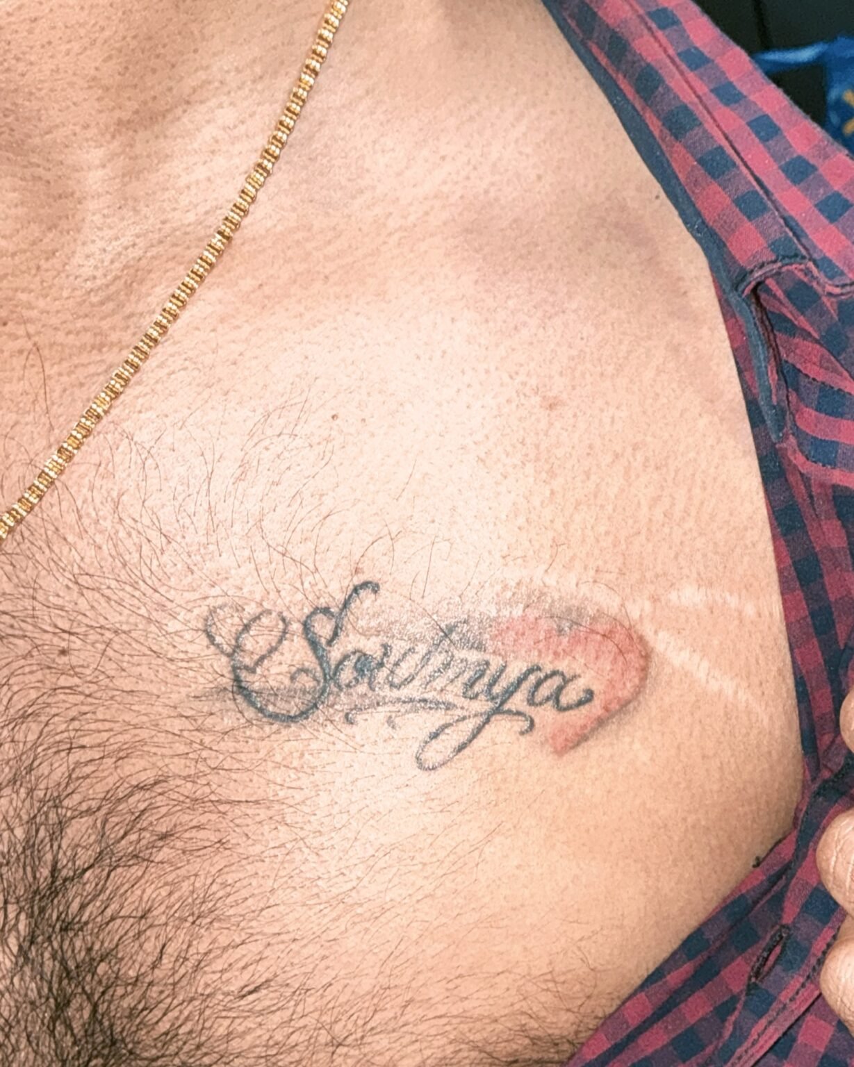 Faded script name tattoo with a small red heart on the chest, before its cover-up at Tattoo Lab, Halifax