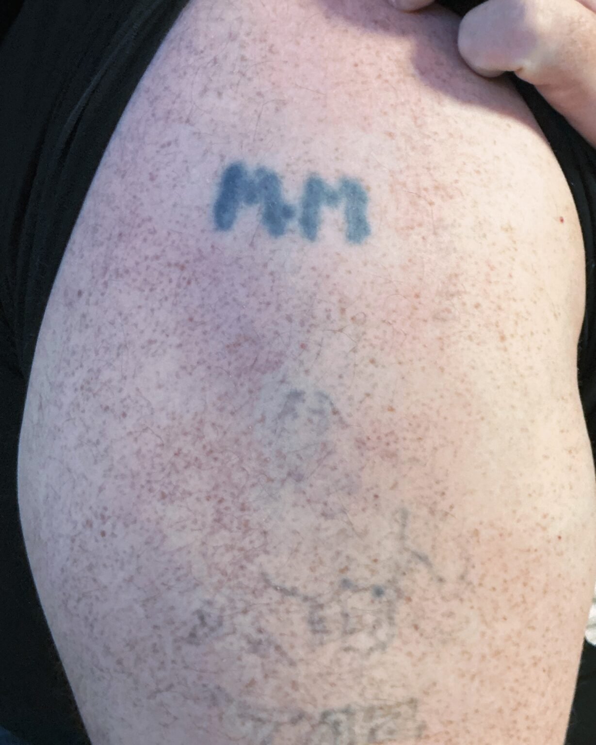 Two blue initials and a faded older tattoo on the shoulder, before the cover-up at Tattoo Lab, Halifax
