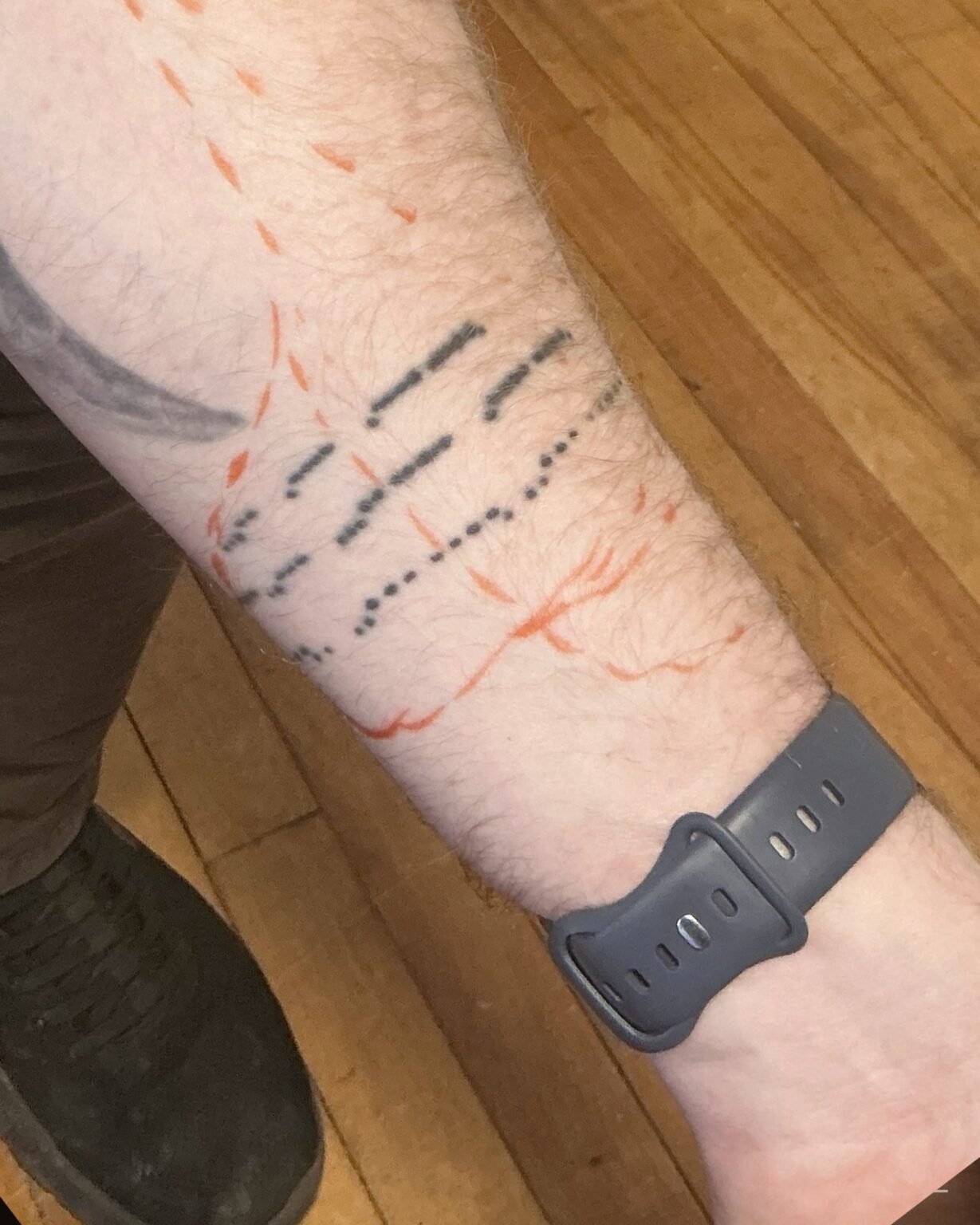 Morse code dots and dashes tattoo on the inner forearm with red stencil lines drawn over it, before its cover-up at Tattoo Lab, Halifax