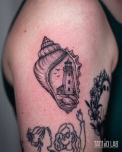 Fine line tattoo of a seashell framing a lighthouse and birds, with dotwork shading, on the upper arm
