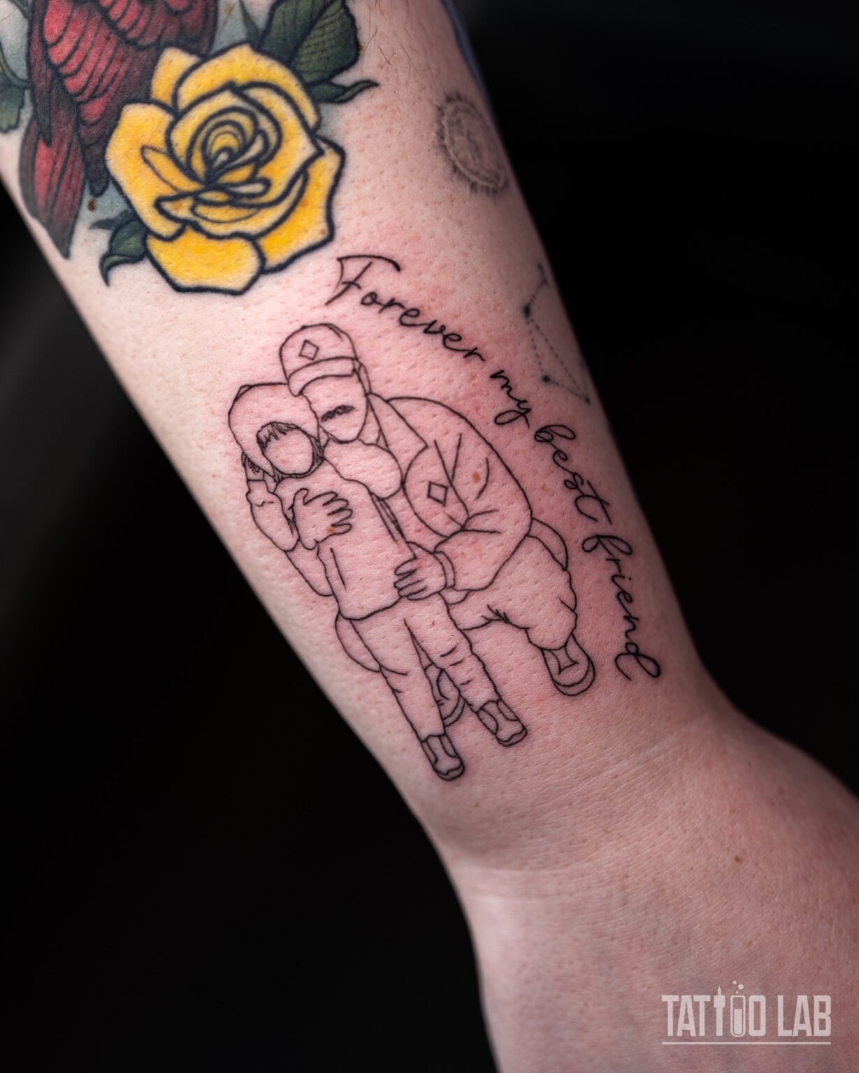 Fine line outline tattoo of an adult hugging a child with "Forever my best friend" script on the inner forearm, Tattoo Lab, Halifax