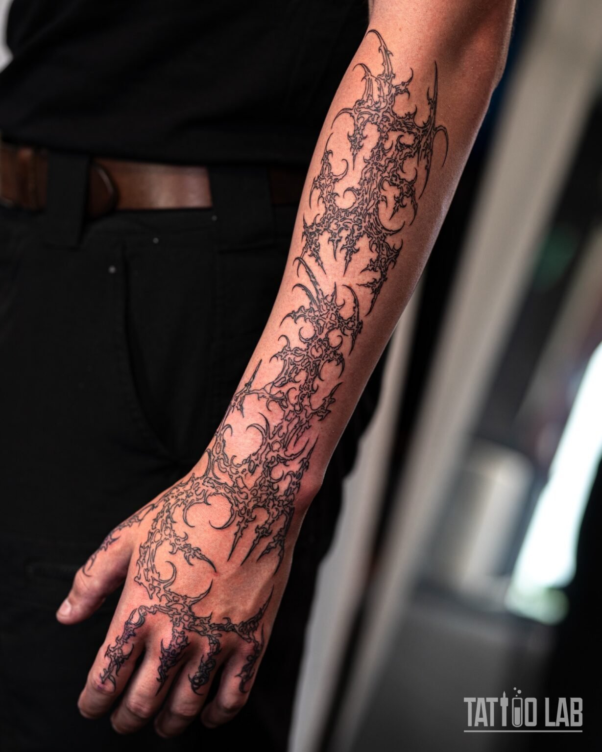 Spiky neo-tribal ornamental linework tattoo in black ink running down the forearm, over the hand and fingers, Tattoo Lab, Halifax